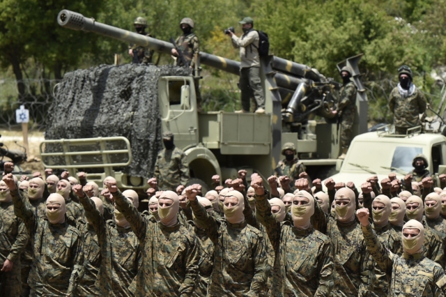 epa10643632 Hezbollah fighters raise their fists as they parade with equipment as part of a training exercise during a press tour to one of the resistance camps ahead of 'Liberation Day' on 25th May in the village of Aaramta, southern Lebanon, 21 May 2023. On 25 May 2000, the Israeli army withdrew from areas of southern Lebanon after 22 years of occupation.  EPA/WAEL HAMZEH